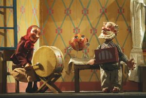 Granny with the drums and Granddad with the lajna instrument, joined by <i>Speckles the Ball</i> who has flown in through the window. The puppets were fabricated by Jan Malik, the performance saw its première at the City Puppet Theatre (today's <!--LINK'" 0:1152-->) in 1951 and became immensely popular around Slovenia.