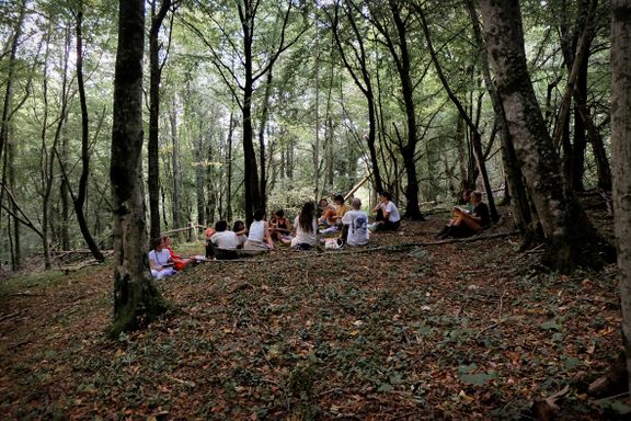 Summer school of the Academy of Margins, a collective learning experience in the village of Topolò (summer 2022). Collective reading moment in the forest.